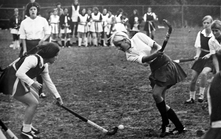 Black and white photograph depicting two girls fighting for the ball during a school field hockey game.