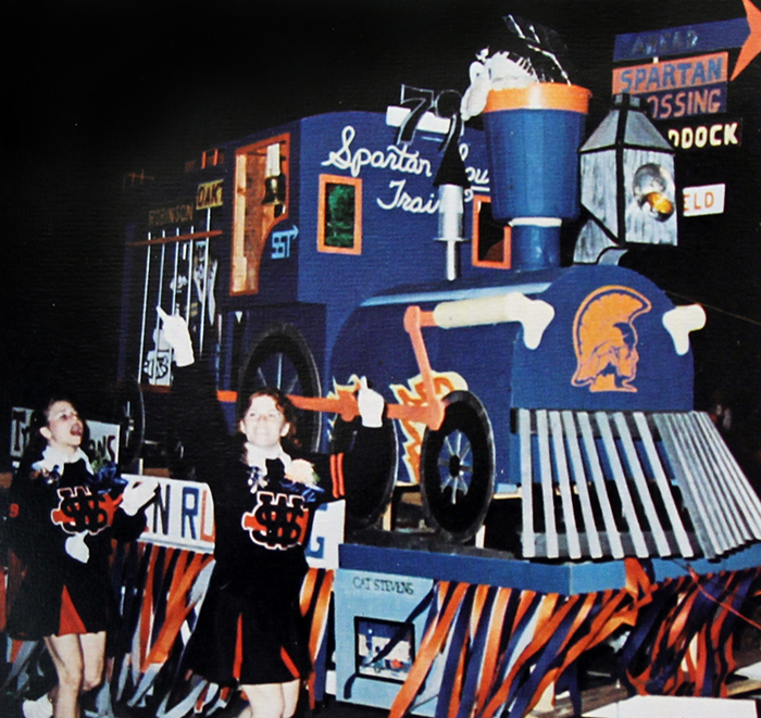 Photograph of the 1978 senior float for the school's annual homecoming parade. The float is decorated with orange and blue, and has been painted to look like a train.