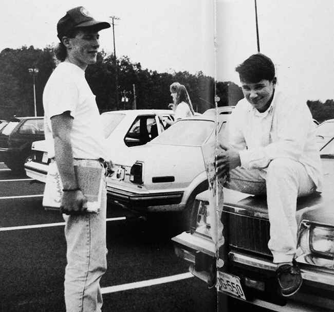 Black and white photo of two students hanging out in the school parking lot after school.