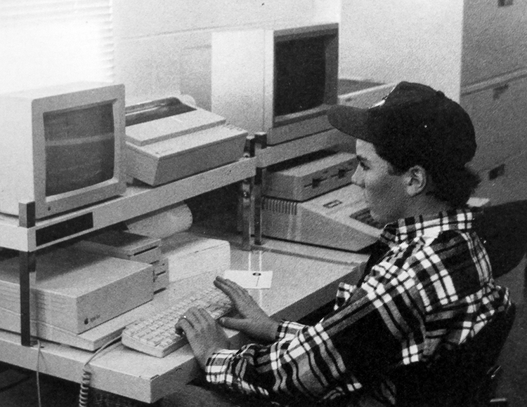Black and white yearbook photograph of a student working at a computer in 1991.